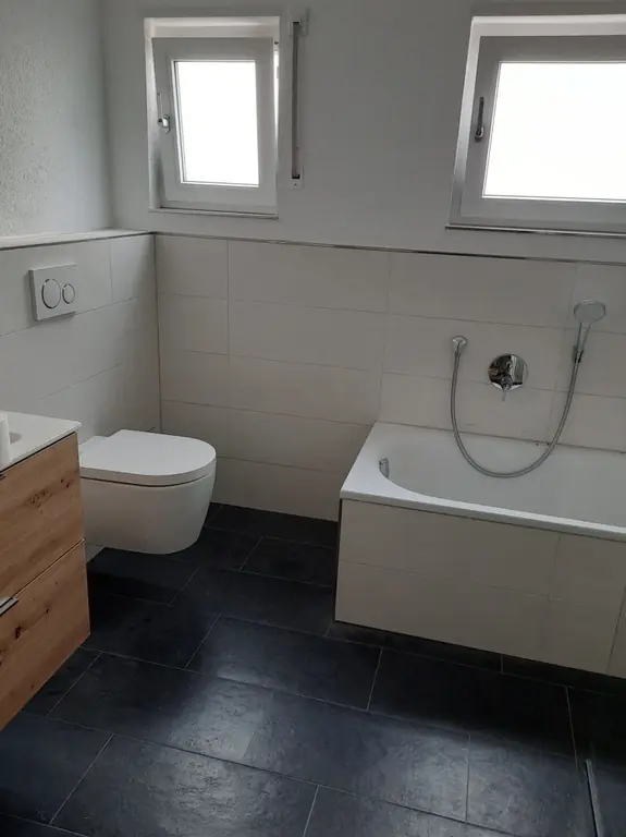 Modernisiertes Bad mit Badewanne und dunklem Fliesenboden – Fliesen Berisha Neulußheim